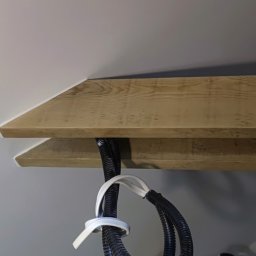 OsBud - Drewniana belka sufitowa z ukrytymi przewodami elektrycznymi, świeżo pomalowana białą farbą, widok z dołu. Estetyczne wykończenie wnętrza.