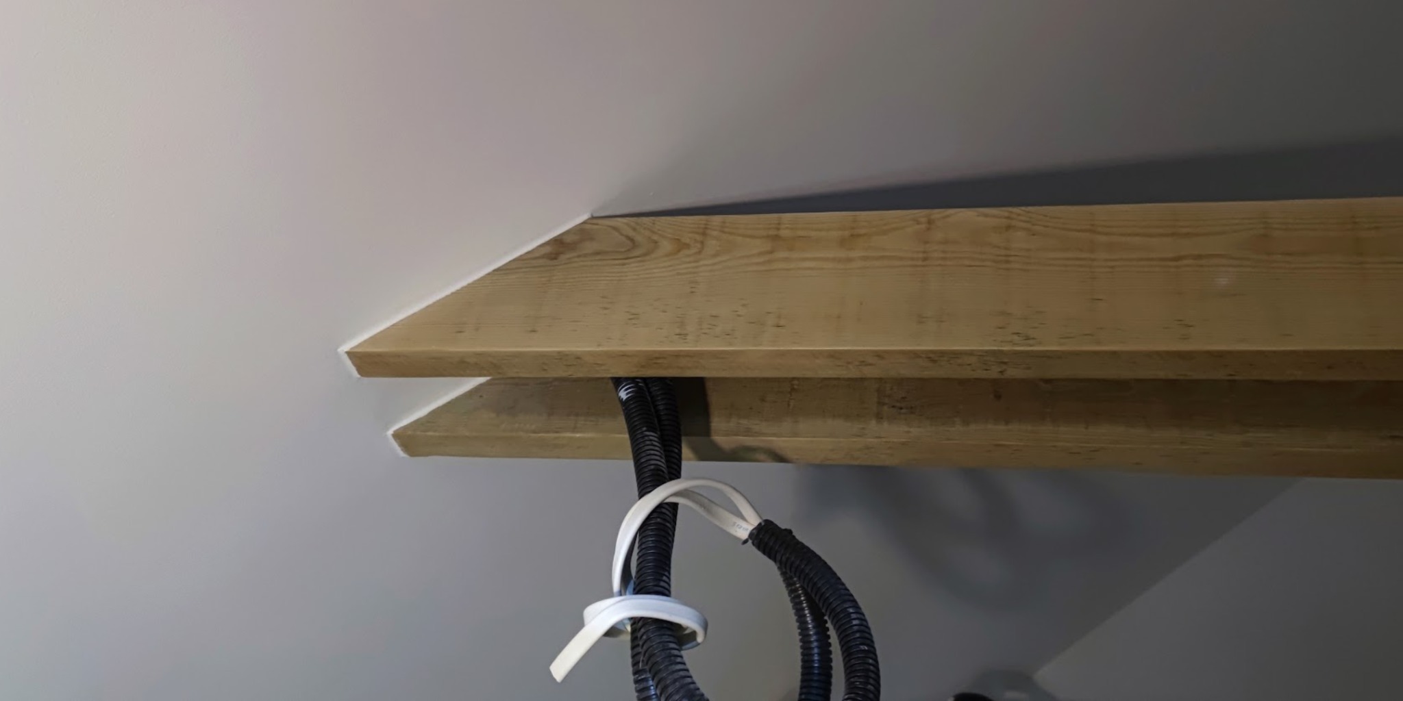 Drewniana belka sufitowa z ukrytymi przewodami elektrycznymi, świeżo pomalowana białą farbą, widok z dołu. Estetyczne wykończenie wnętrza.