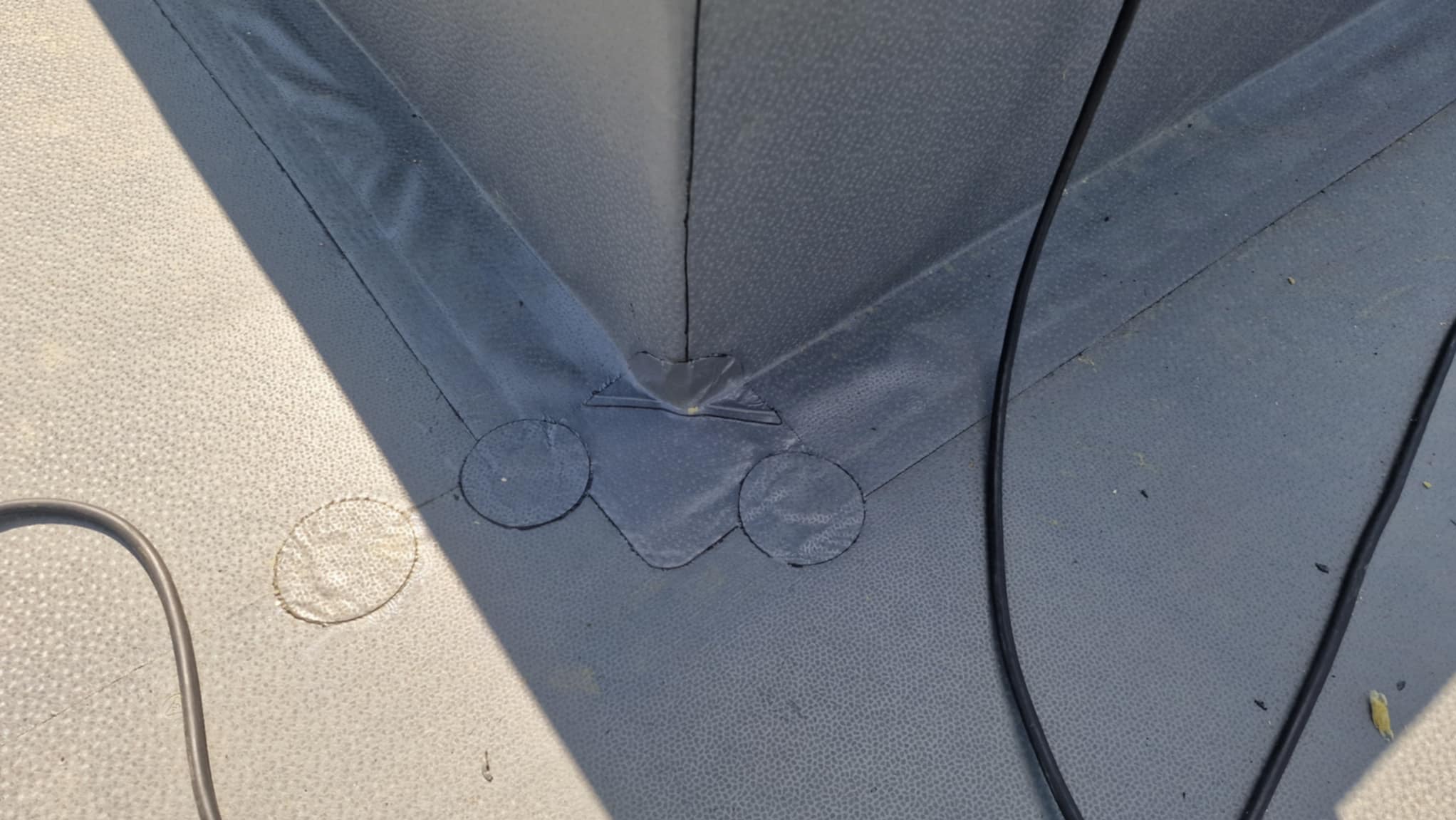 Szczegółowe ujęcie hydroizolacji dachu płaskiego z widocznymi łączeniami i detalami wykończenia, podkreślone przez padające światło słoneczne.