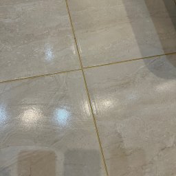 Mirosława Mira - Błyszcząca, świeżo umyta podłoga z płytek ceramicznych w Nysie, z widocznymi smugami wody i refleksami światła.