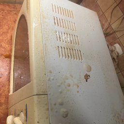 Mirosława Mira - Zabrudzony piekarnik elektryczny przed czyszczeniem, widoczne zaschnięte plamy i tłuszcz na obudowie i wewnątrz. Ujęcie z góry, ukazujące stopień zabrudzenia.