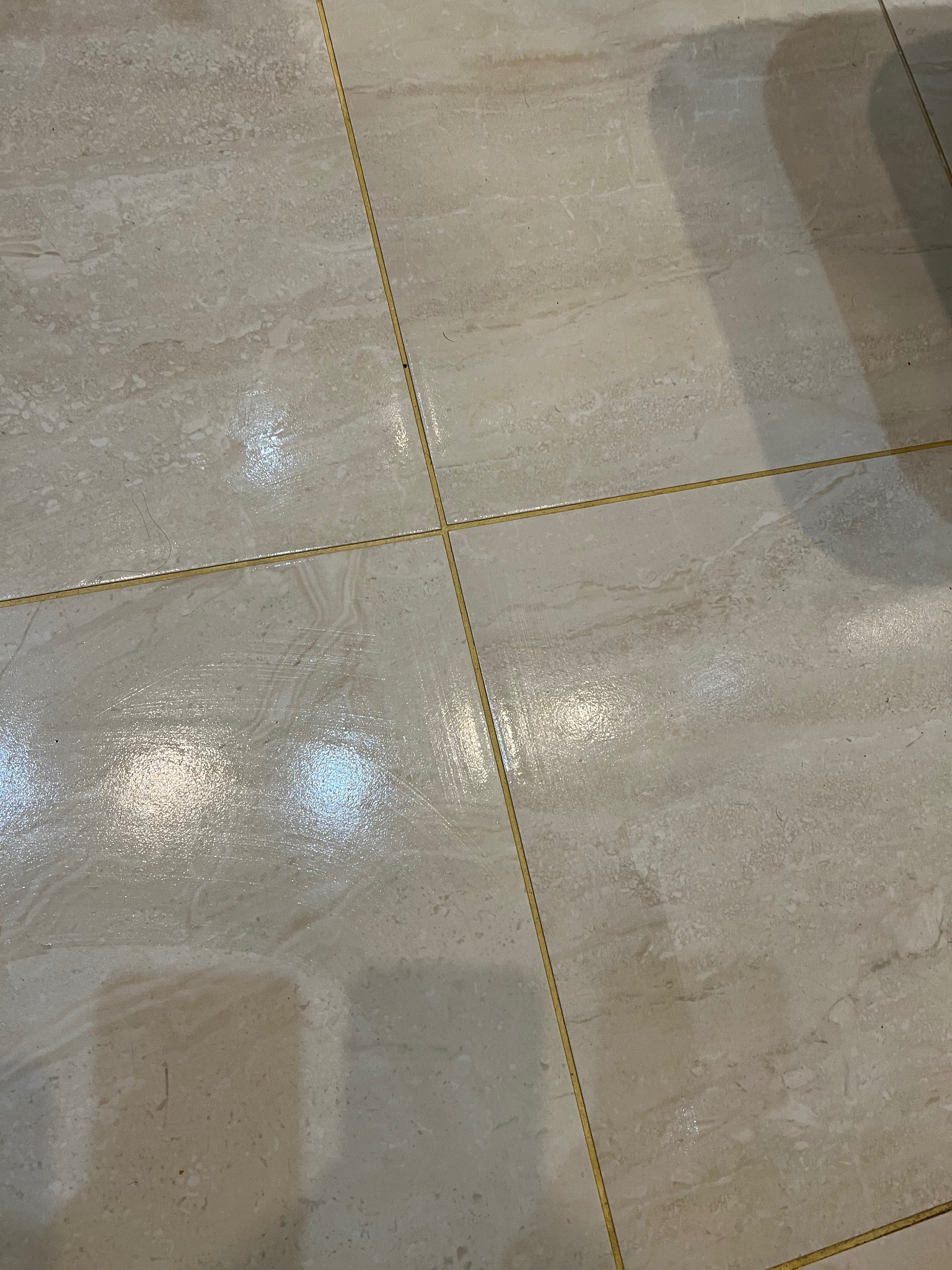 Błyszcząca, świeżo umyta podłoga z płytek ceramicznych w Nysie, z widocznymi smugami wody i refleksami światła.