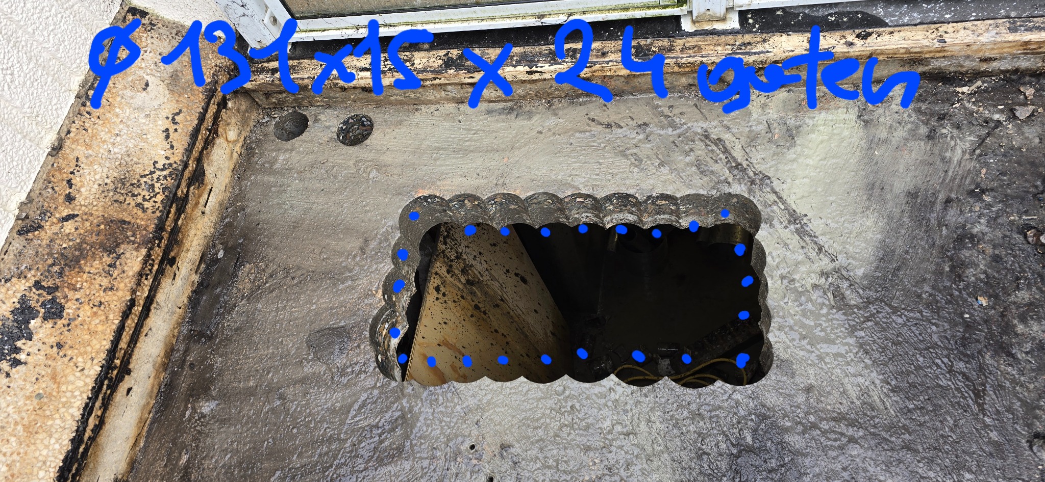 Otwór w betonowej posadzce z zaznaczonymi punktami wiercenia i wymiarami 131x15x24 cm, widoczne elementy instalacji wewnątrz otworu.