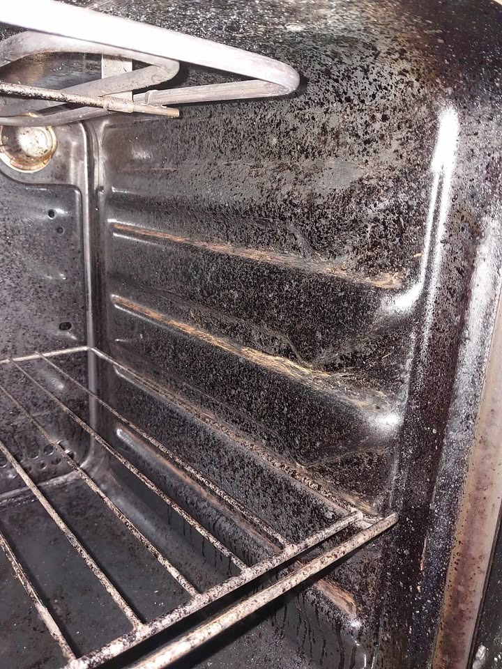 Wnętrze bardzo zabrudzonego piekarnika z przypalonym tłuszczem na ściankach, ruszcie i grzałce. Widoczne osady i resztki jedzenia. Potrzebne gruntowne czyszczenie.