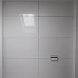 Ściana wyłożona białymi, błyszczącymi panelami z widocznym panelem sterowania i przygotowanym miejscem na instalacje, dolna część ściany z zielonymi płytami gipsowymi i otworami na rury.