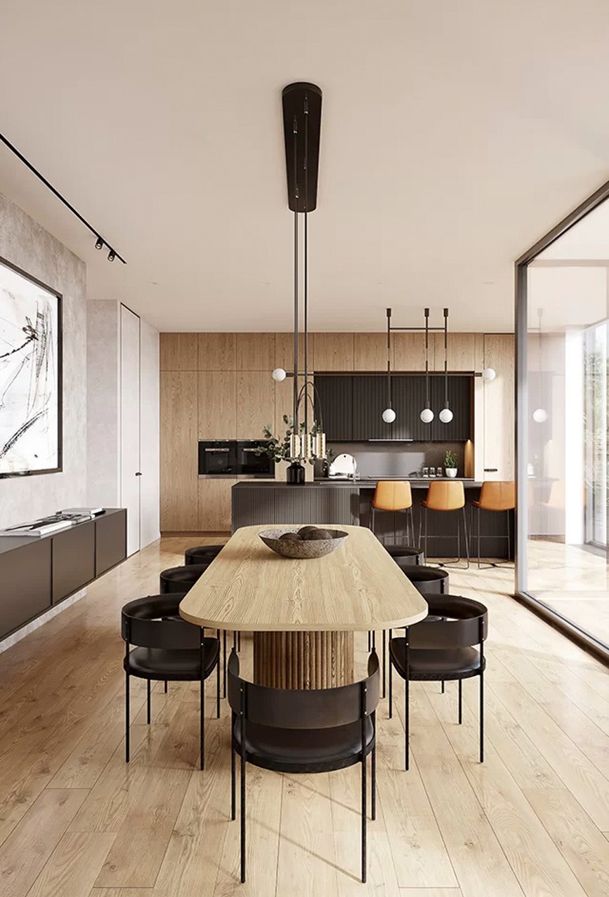 Nowoczesna jadalnia z drewnianym stołem i czarnymi krzesłami. W tle widoczna kuchnia z drewnianymi szafkami i wyspą. Minimalistyczny design, jasne wnętrze.