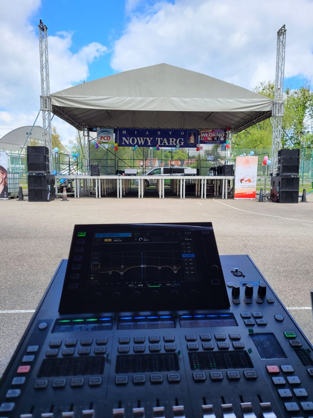 Konsoleta mikserska z widokiem na scenę plenerową w Nowym Targu, z nagłośnieniem i dekoracjami, przygotowaną na wydarzenie miejskie.