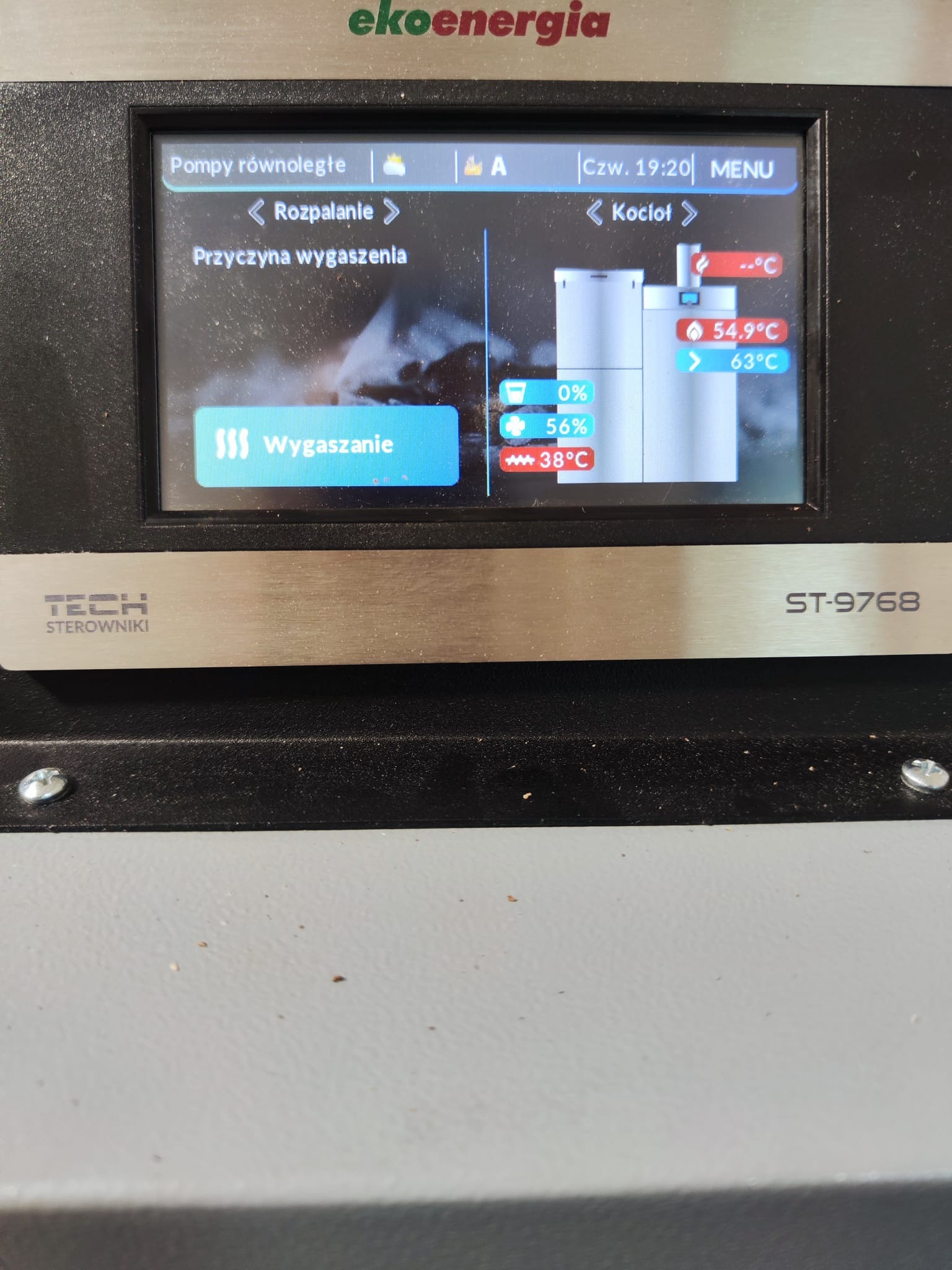 Panel sterowania kotła Ekoenergia ST-9768 z ekranem LCD pokazującym status wygaszania, temperatury i ustawienia pomp. Widoczne menu 'Kocioł' i opcja 'Rozpalanie'.