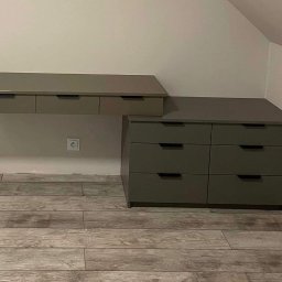 DOMAR - Szara szafka wisząca z trzema szufladami i komoda z sześcioma szufladami w pokoju na poddaszu z drewnopodobną podłogą i gniazdkiem elektrycznym.