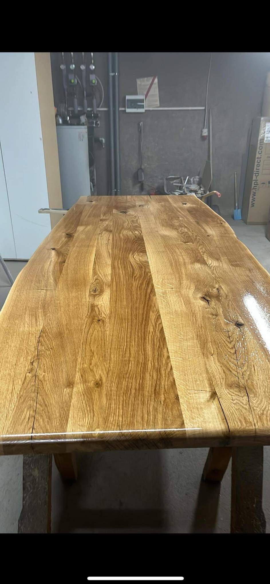 Długi, lakierowany blat drewniany z wyraźnym usłojeniem, osadzony na drewnianej konstrukcji. Widoczne niedoskonałości drewna dodają rustykalnego charakteru.