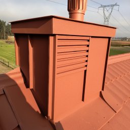 Igor Smirnow - Brązowy komin wentylacyjny z blachy na dachu z blachy trapezowej, w tle słup wysokiego napięcia i drzewa. Widok z góry.