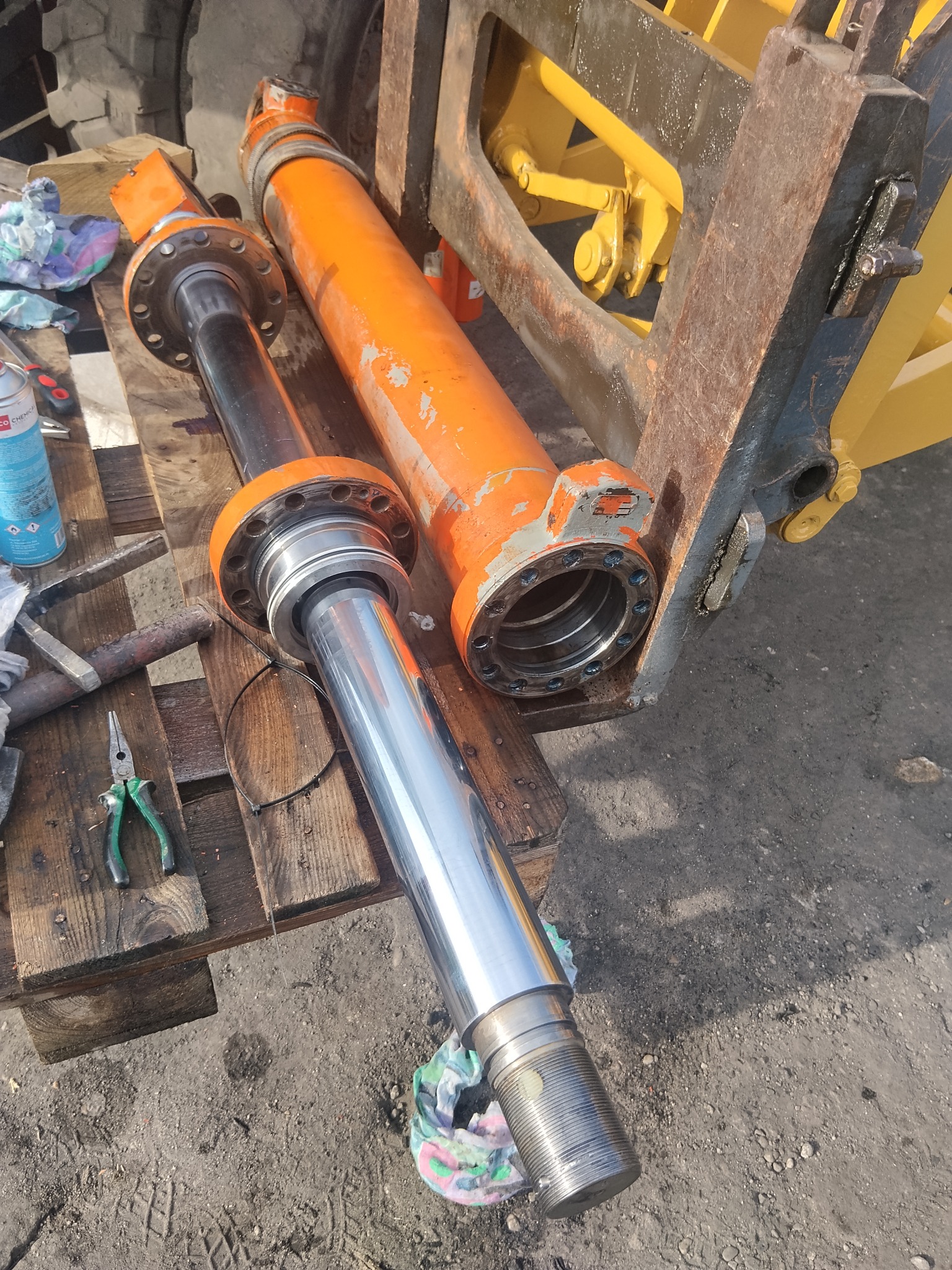 Cylindry hydrauliczne wózka widłowego po regeneracji, leżące na palecie. Widoczne ślady użytkowania na pomarańczowej obudowie i narzędzia.