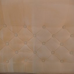 Czyste Meble Alex - Beżowa tapicerka kanapy z guzikami, widoczne plamy i różnice w odcieniach, sugerujące proces czyszczenia. Częściowe ujęcie, skupione na detalu faktury i zabrudzeniach.