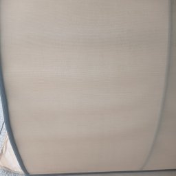 Czyste Meble Alex - Beżowa tapicerka kanapy z ciemną lamówką, widoczna z bliska, po procesie czyszczenia. Delikatna faktura materiału, jasne oświetlenie, czysty i odświeżony wygląd.