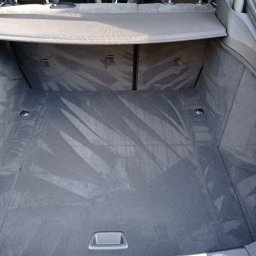 Czyste Meble Alex - Wnętrze bagażnika samochodu z widocznymi śladami po czyszczeniu tapicerki, ukazując efekt usługi. Widoczne detale wykończenia i specyfika materiału.