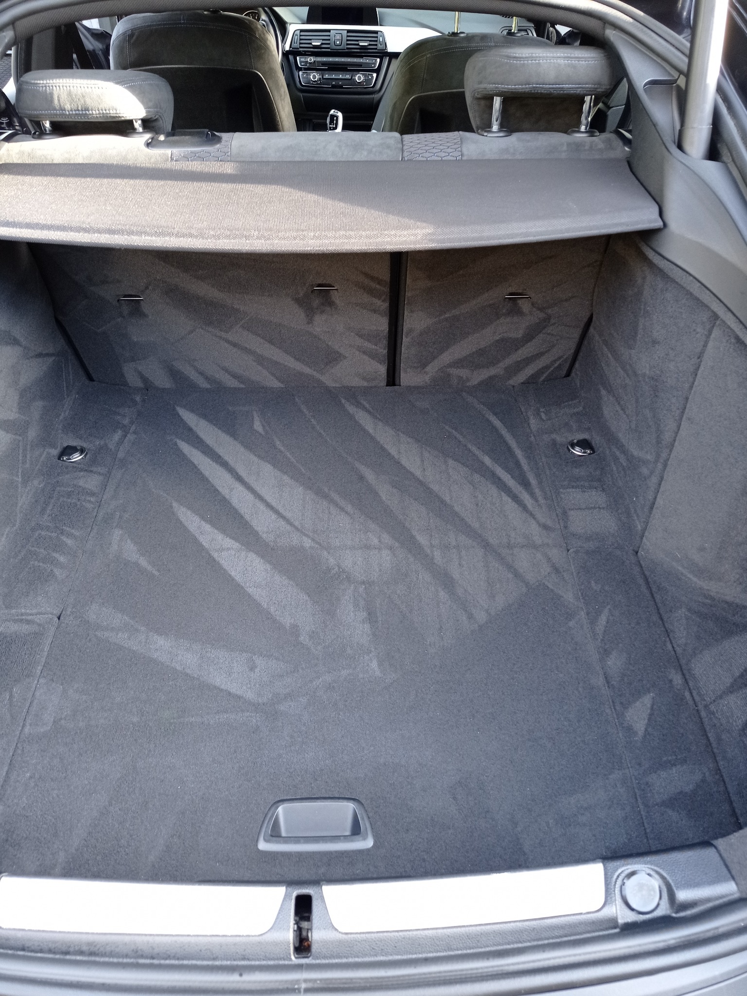 Wnętrze bagażnika samochodu z widocznymi śladami po czyszczeniu tapicerki, ukazując efekt usługi. Widoczne detale wykończenia i specyfika materiału.