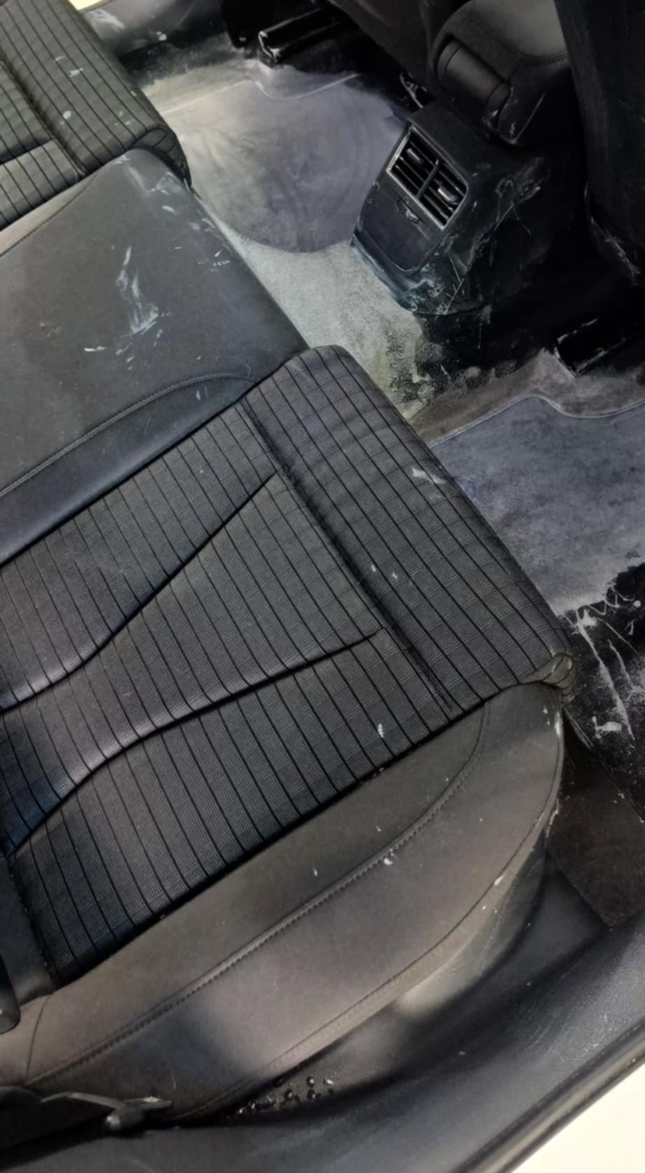 Czyszczenie tapicerki samochodowej: mokre fotele z widocznymi śladami środka czyszczącego, wnętrze pojazdu w trakcie detailingu.