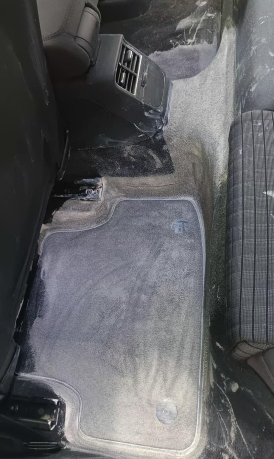 Wnętrze samochodu po czyszczeniu: wyprana podłoga i dywaniki, widoczne detale fotela i nawiewu. Świeżo wyczyszczona tapicerka.