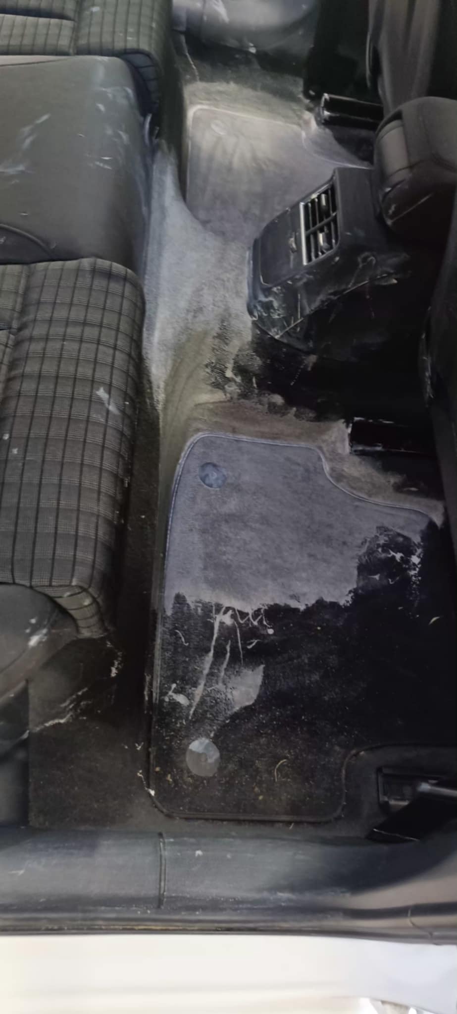 Wnętrze samochodu po praniu tapicerki: mokra podłoga i fotele z widocznymi śladami czyszczenia, plamy usunięte, widoczne detale tapicerki.