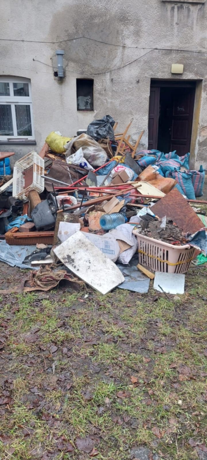 Sterta odpadów i śmieci przed budynkiem w Tarnowskich Górach, widoczne worki, meble, skrzynki i inne pozostałości po remoncie lub opróżnianiu mieszkania.