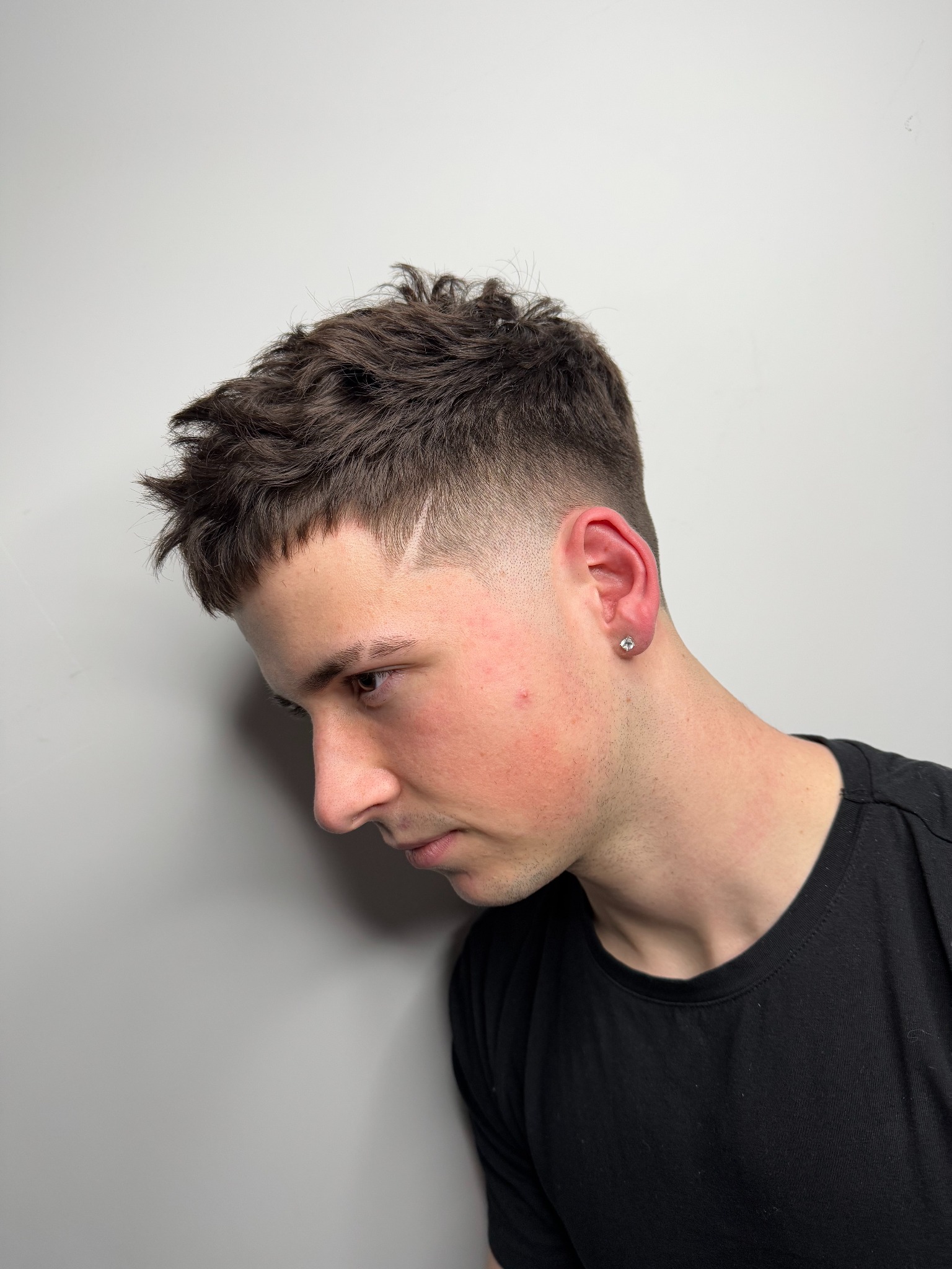 Męska fryzura z krótkimi bokami, delikatnym cieniowaniem i wygolonym wzorkiem, widok z profilu.