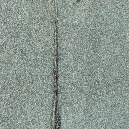 Dachy Płaskie Dawid Karpiak - Fragment dachu pokrytego gontem bitumicznym z widocznym uszkodzeniem i śladami po naprawie, z bliska.