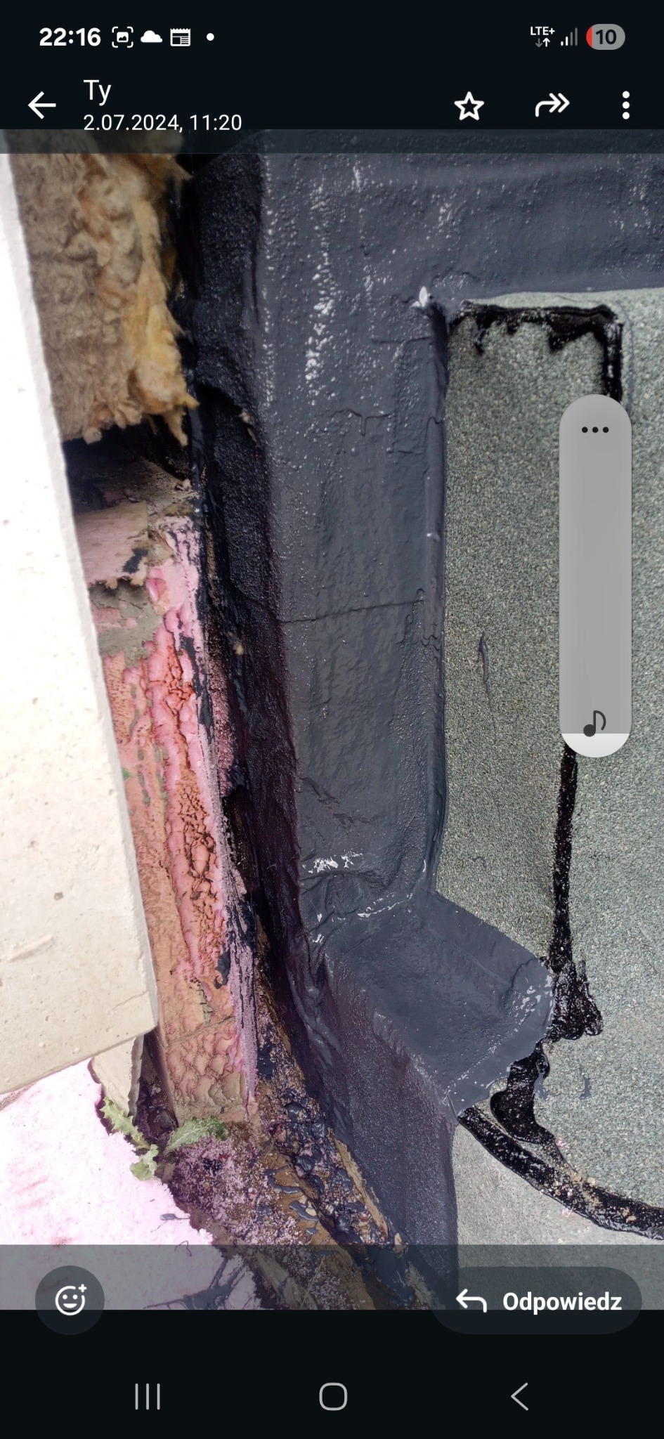 Szczegółowe ujęcie naprawy dachu z użyciem czarnej masy uszczelniającej, widoczne materiały izolacyjne i fragment pokrycia dachowego.