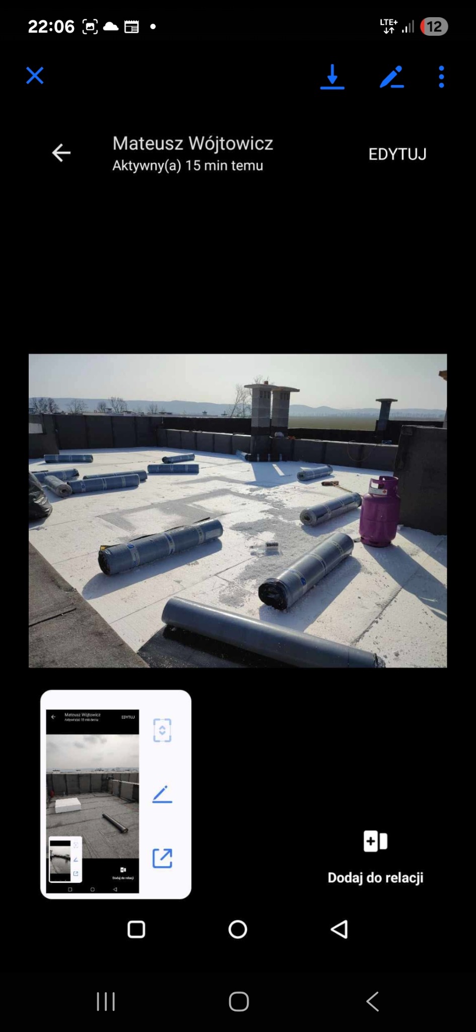 Biały dach płaski z rozłożonymi rolkami papy przed kryciem, widoczny komin i butla gazowa. Przygotowanie do krycia dachu w słoneczny dzień.