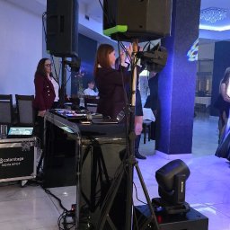 EventXperts - Dawid Krysman - Kobiety konfigurują nagłośnienie i oświetlenie marki Colorstage Nova Spot podczas eventu w sali bankietowej z marmurową posadzką.