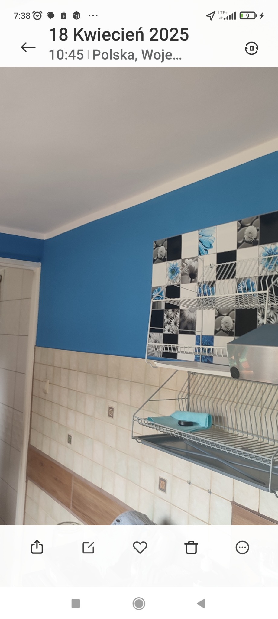 Odnowiona kuchnia z niebieską ścianą, wzorzystymi płytkami i suszarką do naczyń. Ściana pomalowana na intensywny niebieski kolor, dodaje świeżości wnętrzu.