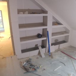 BRK Rafał Kuźdub - Zabudowa poddasza płytą GK z wnękami na półki. Widoczne narzędzia i resztki materiałów budowlanych. Prace wykończeniowe w domu jednorodzinnym.