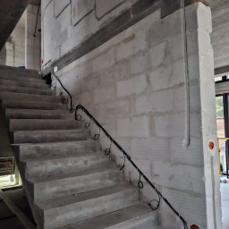 Smart Elektro Dawid Kowalski - Betonowe schody w surowym stanie z poprowadzoną instalacją elektryczną w peszlach, widoczne puszki elektryczne w ścianie z betonu komórkowego.