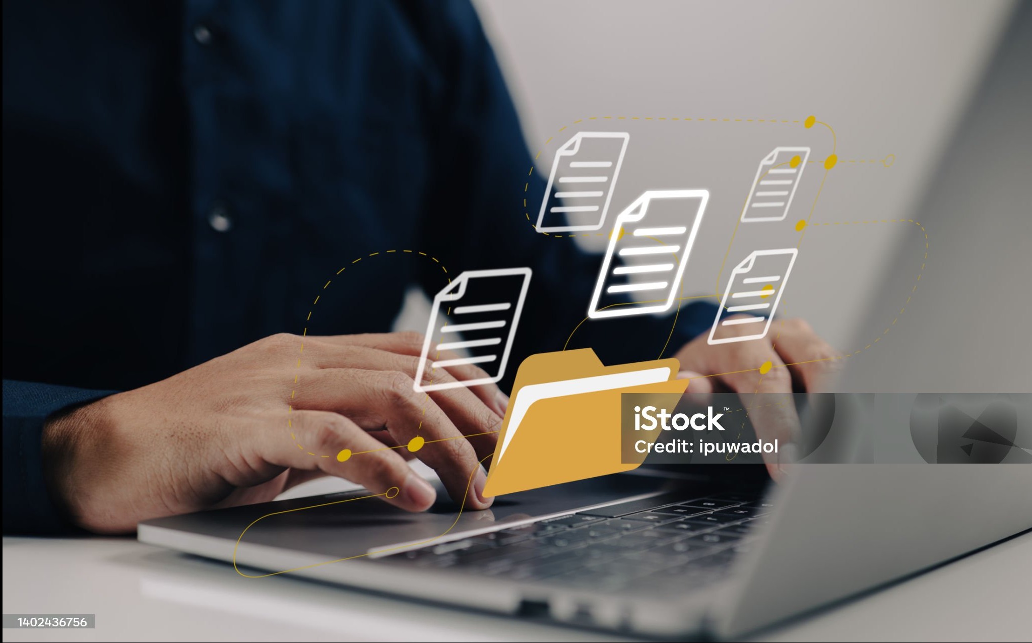 Praca na laptopie z grafiką folderu i dokumentów, symbolizująca zarządzanie danymi i procesy kadrowe. Dłonie na klawiaturze, stonowana kolorystyka.