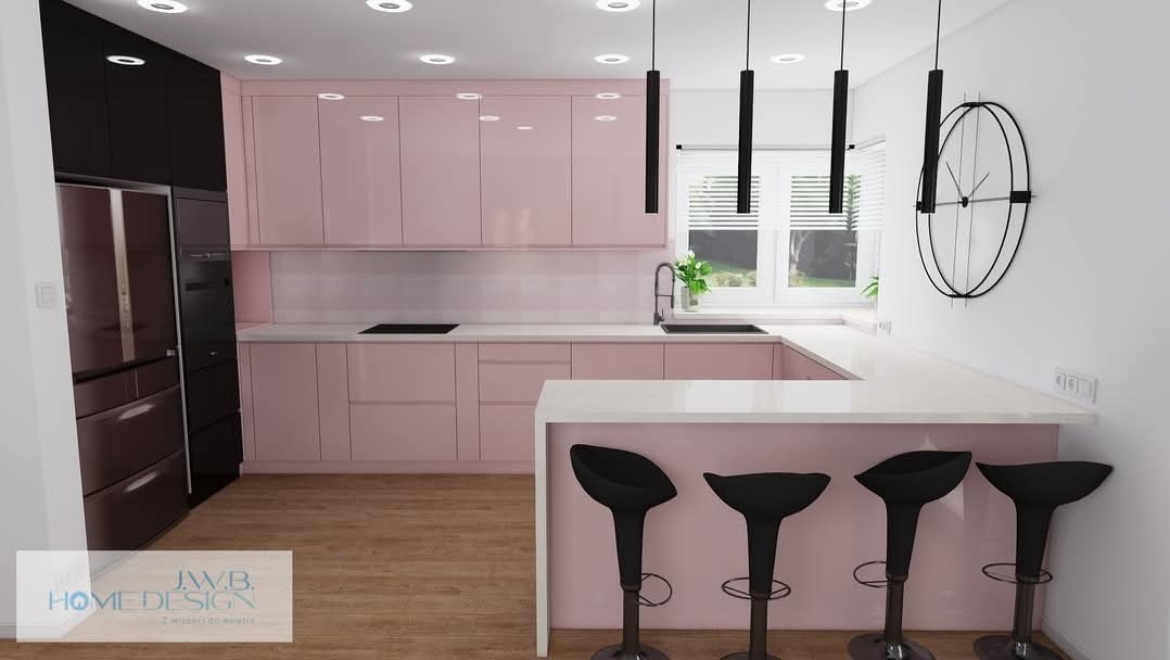 Nowoczesna kuchnia w odcieniach różu i czerni z wyspą, oświetleniem punktowym i wiszącymi lampami. Minimalistyczny zegar na ścianie dodaje charakteru.