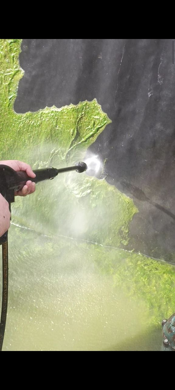 Proces czyszczenia ścian stawu z glonów.