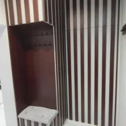 Nowoczesna zabudowa przedpokoju z siedziskiem i wieszakami, wykończona pionowymi panelami w odcieniach brązu i bieli, na tle marmurowej posadzki.