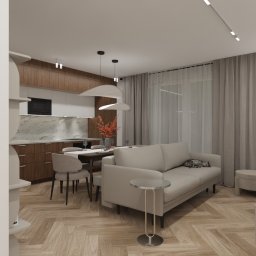 Preludium Design Patrycja Gawryszewska - Jasne wnętrze z drewnianą podłogą w jodełkę. W tle kuchnia z drewnianymi szafkami i marmurowym blatem, stół z krzesłami i szara sofa z kotem. Minimalistyczny design.