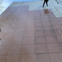 Sebastian Dudek Hyper-Tech - Pracownik alpinistyczny myje elewację budynku z płytek, widoczne różnice czystości. Prace wysokościowe z użyciem sprzętu alpinistycznego i lancy ciśnieniowej.