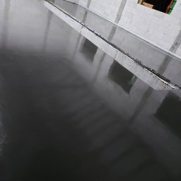 Posadzki Nowy Tomyśl - Świeżo wylana, ciemna posadzka przemysłowa, z widoczną listwą dylatacyjną w surowym wnętrzu budynku z białego bloczka.