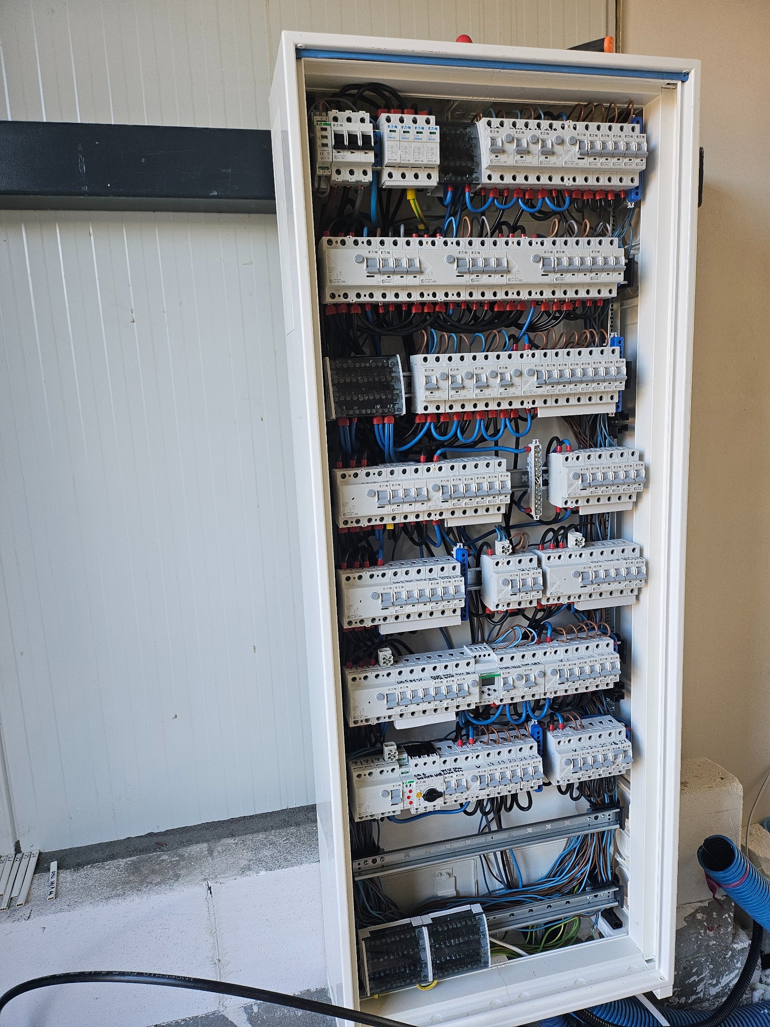 Rozdzielnia elektryczna z zabezpieczeniami i okablowaniem w białej obudowie, zamontowana w Legionowie. Widoczne bezpieczniki i przewody.