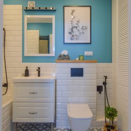 Twój Dom - Estetyczna aranżacja łazienki z turkusową ścianą, białymi płytkami imitującymi cegłę i szafką umywalkową na metalowych nóżkach. Uwagę przykuwają wzorzyste płytki podłogowe.