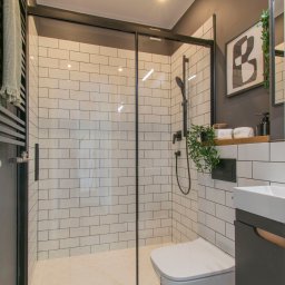 Twój Dom - Nowoczesna łazienka z kabiną prysznicową typu walk-in, białą armaturą i wzorzystą podłogą. Ciemne ściany kontrastują z jasnymi płytkami.