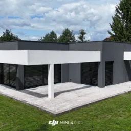 Nowoczesny dom jednorodzinny z płaskim dachem i tarasem w Słupcy, sfotografowany z drona. Minimalistyczna architektura, szara elewacja, białe elementy konstrukcyjne.