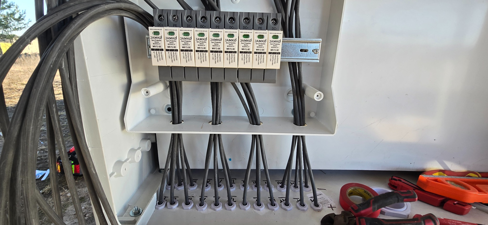 Wnętrze skrzynki z zabezpieczeniami DC instalacji fotowoltaicznej. Widoczne moduły JAMKO, przewody i narzędzia monterskie. Precyzyjne połączenia i estetyka wykonania.