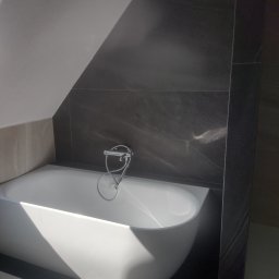 Tomasz Dąbrowski Arsen Usługi Glazurnicze - Nowoczesna łazienka na poddaszu: biała wanna, ciemnoszare płytki imitujące marmur, bateria wannowa. Ukończony remont łazienki z nietypowym skosem.