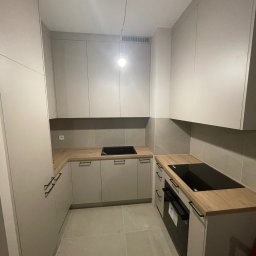 Almal - Jasna, nowoczesna zabudowa kuchenna z drewnianym blatem i czarnymi uchwytami, widok z góry. Realizacja w Warszawie.