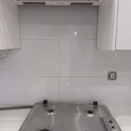 Biała kuchnia po sprzątaniu: płyta gazowa Amica, błyszczące płytki, czysty okap i puste gniazdko elektryczne. Widok z góry na uporządkowaną przestrzeń.