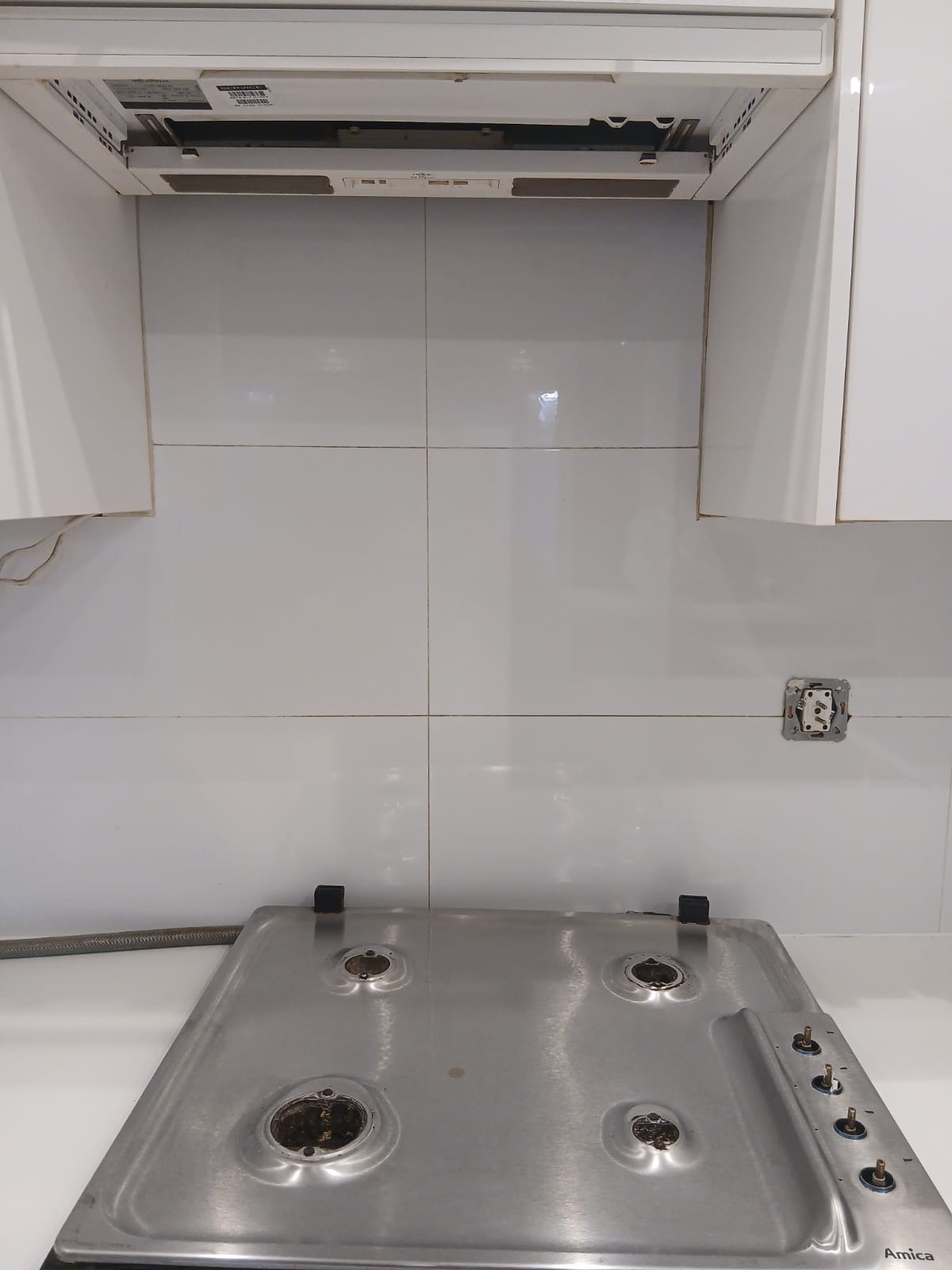 Biała kuchnia po sprzątaniu: płyta gazowa Amica, błyszczące płytki, czysty okap i puste gniazdko elektryczne. Widok z góry na uporządkowaną przestrzeń.