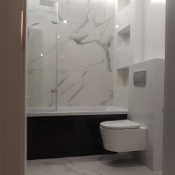 Rubi-Bud - Nowoczesna łazienka z biało-czarnymi płytkami imitującymi marmur, podwieszaną toaletą i wnękami w ścianie. Kabina prysznicowa ze szklanym panelem.