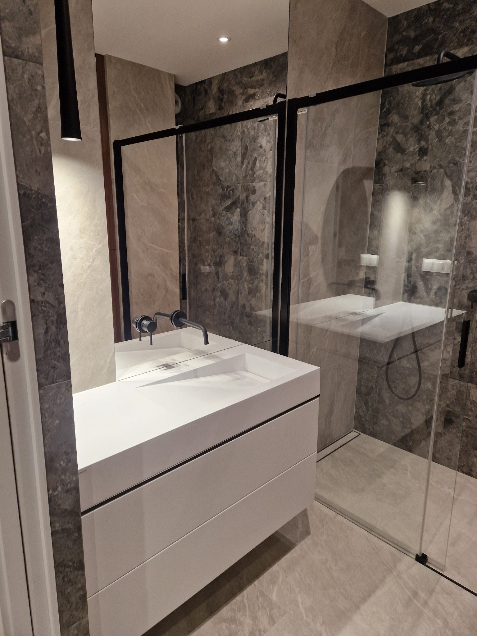 Nowoczesna łazienka w Lublinie z kabiną typu walk-in, białą umywalką nablatową i szarą, marmurkową okładziną ścian oraz podłogi.